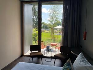 a bedroom with a large window with a table and chairs at Hôtel Restaurant Port-Conty in Saint Aubin Sauges