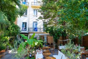 einen Innenhof mit Tischen, Stühlen und Bäumen in der Unterkunft Auberge de Jeunesse HI Nice Les Camélias in Nizza