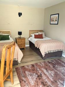 a bedroom with two beds and a rug at Kingfisher Barn B&B in Abingdon