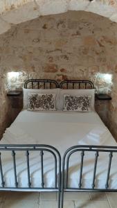 Bett in einem Zimmer mit einer Steinmauer in der Unterkunft Trullo Titti in Ostuni