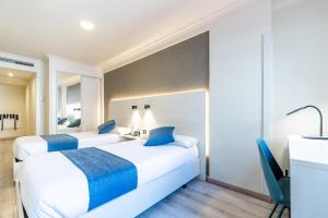 a hotel room with two beds and a desk at Hotel Atlántico Vigo in Vigo