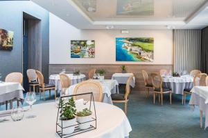 a dining room with white tables and chairs at Logis Auberge De La Sélune in Ducey