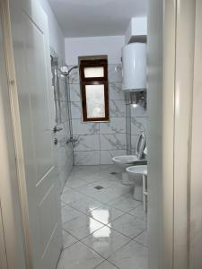 a white bathroom with a toilet and a sink at Orchidea Apartment in Pogradec