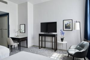 a hotel room with a television and a desk and chairs at London Marriott Hotel Grosvenor Square in London