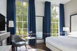 ein Schlafzimmer mit blauen Vorhängen sowie einem Bett und einem Stuhl in der Unterkunft London Marriott Hotel Grosvenor Square in London