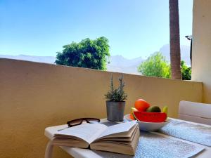 an open book sitting on a table with a bowl of fruit at Mareverde Blue Studio Tenerife in Adeje