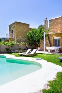 - une piscine avec 2 chaises longues et une maison dans l'établissement Sonio Villas - Que Bella Collection, à Platanias