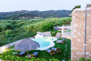 a backyard with a swimming pool with chairs and an umbrella at Sonio Villas - Que Bella Collection in Platanias