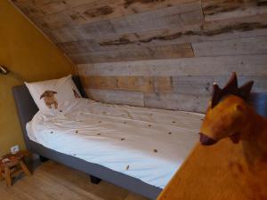 a small bed in a room with a wooden wall at B&B Clogher Farm in Poperinge