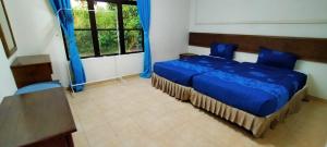 a bedroom with a blue bed and a window at SHA GATHERING ALOR GAJAH BUNGALOW, A FAMOSA MELAKA in Melaka