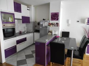 a kitchen with purple and white cabinets and a table at A romantic getaway in Varaždin in Varaždin