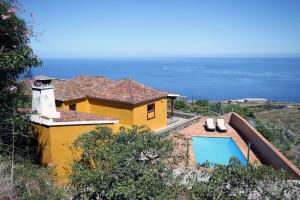 a yellow house with a swimming pool next to the ocean at Lina in Puntallana