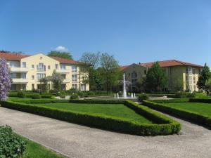 une rangée de haies dans un parc avec des bâtiments dans l'établissement City Hotel Dresden Radebeul, à Radebeul