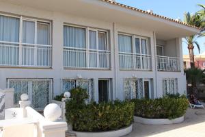 un bâtiment blanc avec des fenêtres et des plantes devant lui dans l'établissement Hotel La Riviera, à Albir