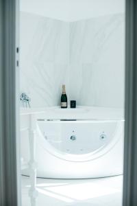 Les Précieuses Suites & Spa II في أفينيون: طاولة بيضاء مع زجاجة من النبيذ عليها
