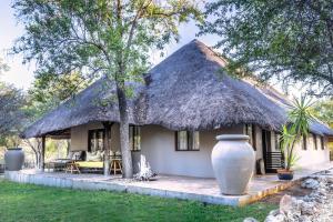Una casa con techo de paja y un jarrón delante. en Mushara Lodge, en Namutoni