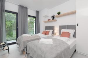 米泽德沃兹Little Laguna Apartments SPA & Gym by Noclegi Renters的一间有两张床和一扇大窗户的卧室