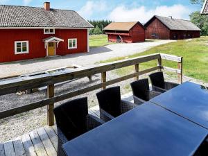 a table and chairs on a deck with a barn at 16 person holiday home in P LSBODA in Hjortkvarn