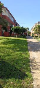 a grassy field next to a building and a street at Ona Apart por Día - Departamentos con cochera in Corrientes