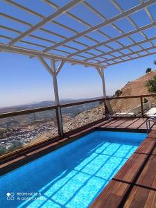 a swimming pool with a pergola and a view at צימר ענאן בגולן in Majdal Shams