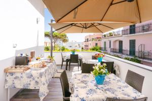 a patio with tables and chairs and an umbrella at Lo Scuncino in Procida