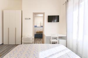 a white bedroom with a bed and a desk at Lo Scuncino in Procida