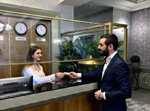 un hombre estrechando la mano con una mujer en una caja registradora en Vegas Hotel, en Akhalk'alak'i