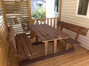 un banc en bois installé sur la terrasse couverte à l'avant d'une maison dans l'établissement Mobilhome 6 pers avec Clim, à Saint-Georges-de-Didonne