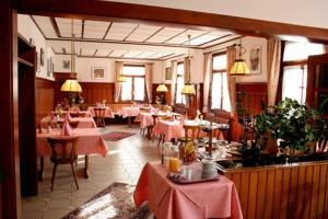 un restaurant avec des tables, des chaises et des tissus de table roses dans l'établissement Hotel Restaurant Adler Bühlertal, à Bühlertal