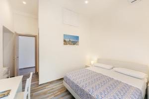 a white bedroom with a bed and a table at Lo Scuncino in Procida