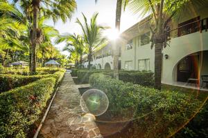 a building with palm trees and a stone walkway at Lovely Condo near monkey habitat and beach in Quepos