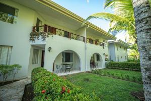 a large white house with a patio and a yard at Lovely Condo near monkey habitat and beach in Quepos