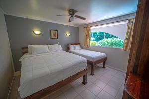 1 dormitorio con 2 camas y ventana en Lovely Condo near monkey habitat and beach, en Quepos