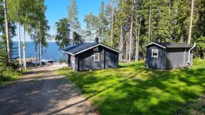 two small buildings in the grass next to a road at Mukava pieni 2-4h mökki min 2 vrk Saimaan rannalla, poreallas, puusauna, Wi-Fi, Smart TV, parivuode ja vuodesohva in Savonlinna +34 photos