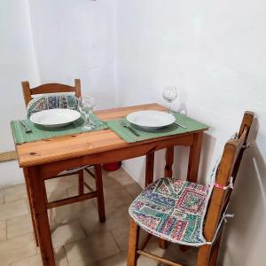 a wooden table with two plates and wine glasses on it at Maroudas Traditional Guest House in Vathi