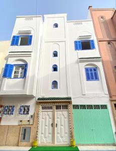 uma casa branca com uma garagem verde em WELKAM Home & Coworking em Essaouira