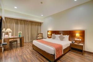 una camera d'albergo con un grande letto e una scrivania di Hotel Home In By Amrik Sukhdev a Sonipat
