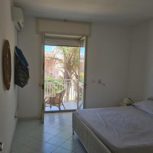 トッレ・デル・オルソにあるAppartamento Gentileのベッドルーム1室(ベッド1台付)、バルコニーへのドアが備わります。