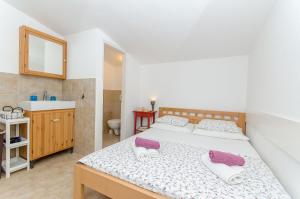 ein Schlafzimmer mit Bett und ein Badezimmer mit Waschbecken in der Unterkunft House Branimir in Kolan