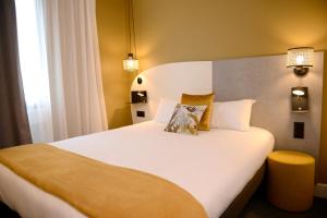 a bedroom with a large white bed with yellow walls at Hôtel Villa Berlioz in Lyon