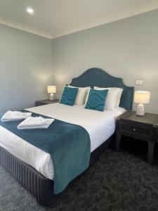 a bedroom with a large bed with blue sheets and pillows at Town & Country Motor Inn in Forbes