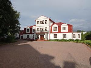 a large white house with a red roof at Dworek Morski in Kołobrzeg