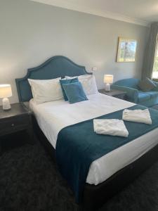 um quarto com uma cama grande e um sofá azul em Town & Country Motor Inn em Forbes