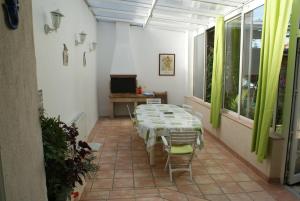 a room with a table and chairs in a room with green curtains at Spacieuse maison de village climatisée avec jardin patio in Bessan