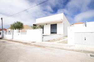 una casa blanca con vallas blancas en una calle en Beach Villa Lagoa de Albufeira II, en Lagoa de Albufeira