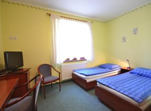 a bedroom with two beds and a desk and a television at Dworek Morski in Kołobrzeg