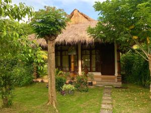 una casa con techo de paja y patio en Budi Sun Resort, en Maumere