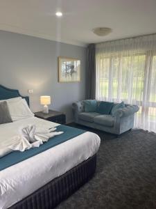 une chambre d'hôtel avec un lit et un canapé dans l'établissement Town & Country Motor Inn, à Forbes