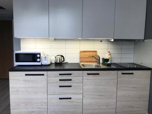 a kitchen with white cabinets and a microwave and a sink at Apartment II GrayFor2 Old Town Kraków in Krakow