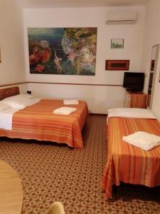 a hotel room with two beds and a painting on the wall at Gavila's Residenza Turistico Alberghiera in Porto Azzurro